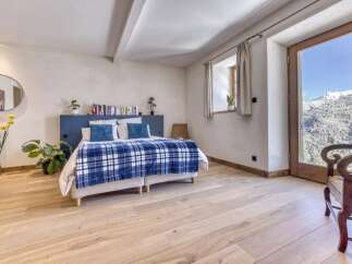 Experience breathtaking mountain views from this charming bedroom, featuring a cozy bed adorned with a blue plaid blanket and a stylish blue headboard.