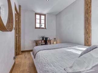 Experience rustic charm in this cozy bedroom featuring exposed wooden beams and a charming wooden desk area.