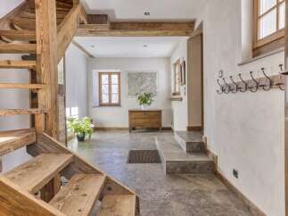 Discover rustic charm in this entryway featuring a beautiful wooden staircase and exposed beams.