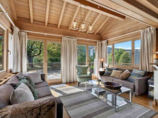 Experience breathtaking mountain views from this stunning living room, featuring a vaulted wood-paneled ceiling and expansive windows that flood the space with natural light.