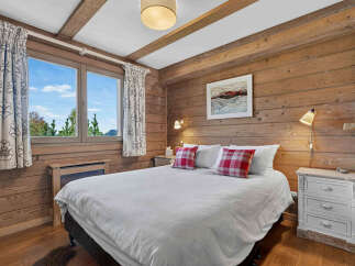 Experience cozy mountain living in this charming bedroom featuring rustic wood-paneled walls and exposed beams.