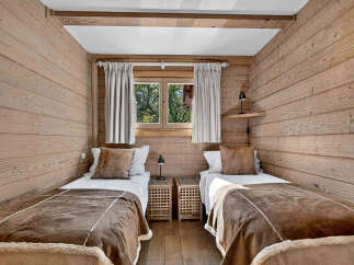Experience cozy mountain living in this charming bedroom featuring two twin beds with plush brown throws and decorative pillows.