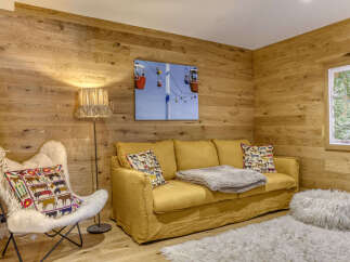 Experience cozy mountain living in this charming room featuring warm wood-paneled walls and a comfortable yellow sofa.