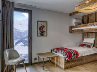 Experience cozy mountain living in this charming bedroom featuring a rustic bunk bed and a plush, sheepskin accent chair.