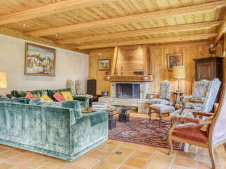 Experience rustic charm in this inviting living room, featuring a grand stone fireplace and exposed wooden beams on the ceiling.