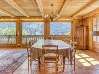 Experience breathtaking mountain views from this charming dining room, featuring a large wooden table perfect for family gatherings.