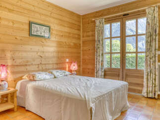Experience serene mountain living in this charming wooden-paneled bedroom.