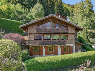 Experience alpine living in this stunning wooden chalet nestled amidst lush greenery and mature trees.