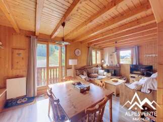 Experience cozy mountain living in this charming wooden chalet, featuring a spacious living area with a fireplace and comfortable seating.