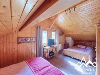 Experience cozy living in this charming attic bedroom, featuring warm wooden paneling throughout and a sloped ceiling that adds to its unique character.