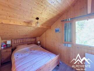 Experience cozy living in this charming wooden cabin bedroom, featuring a comfortable bed adorned with a nature-themed duvet.