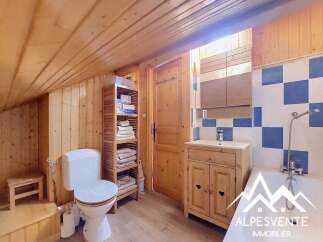 Discover this charming bathroom featuring a classic white toilet and a wooden vanity with a white countertop and sink.