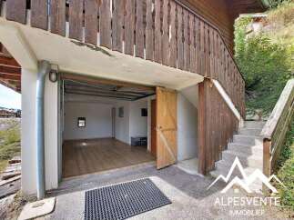 Discover this charming property featuring a spacious garage with a wooden door, perfect for vehicle storage or as a workshop.
