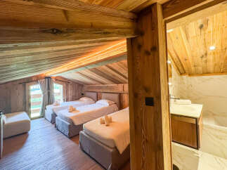 Experience rustic charm and modern comfort in this attic bedroom, featuring three cozy beds perfect for families or groups.
