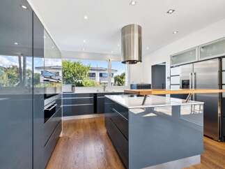 Experience modern luxury in this stunning kitchen, featuring sleek, high-gloss grey cabinetry and a spacious island with a built-in wooden breakfast bar.