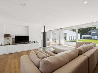 Experience modern luxury in this spacious living room, featuring a sleek entertainment center and a striking cylindrical fireplace.