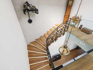 Experience timeless elegance in this stunning home, featuring a grand spiral staircase with intricate wrought-iron railings and warm wooden treads.