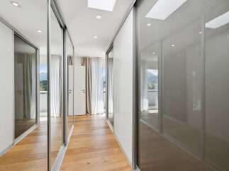 Step into this modern hallway featuring sleek, mirrored sliding doors that amplify the natural light and create a sense of spaciousness.