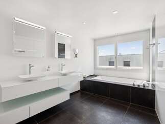 Experience modern luxury in this spacious bathroom featuring dual vessel sinks atop a sleek white vanity.