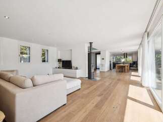Experience modern living in this spacious open-concept home, featuring a bright living area with a comfortable sectional sofa and a sleek entertainment center.