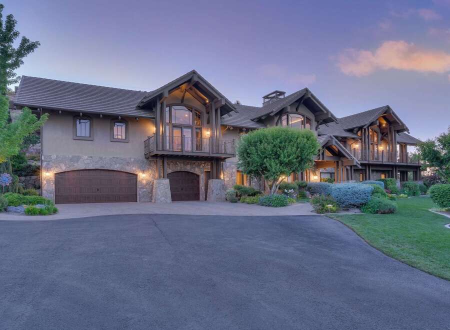 Experience luxury living in this stunning custom-built estate, featuring a grand facade with stone accents and multiple garage bays.