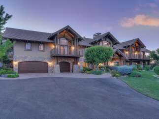Experience luxury living in this stunning custom-built estate, featuring a grand facade with stone accents and multiple garage bays.
