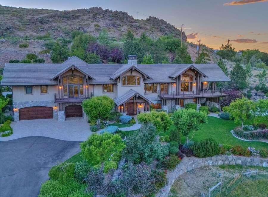 Experience luxury living in this stunning mountain estate, featuring a grand entrance, expansive windows, and multiple balconies offering breathtaking views.