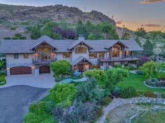 Experience luxury living in this stunning mountain estate, featuring a grand entrance, expansive windows, and multiple balconies offering breathtaking views.