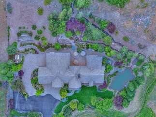 Discover this stunning estate featuring a luxurious home with a sprawling paver driveway and a beautifully manicured lawn.