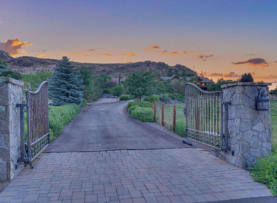 Welcome to this stunning estate, accessed through grand wrought-iron gates set atop elegant stone pillars.