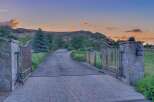 Welcome to this stunning estate, accessed through grand wrought-iron gates set atop elegant stone pillars.