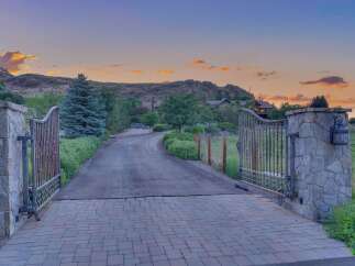Welcome to this stunning estate, accessed through grand wrought-iron gates set atop elegant stone pillars.