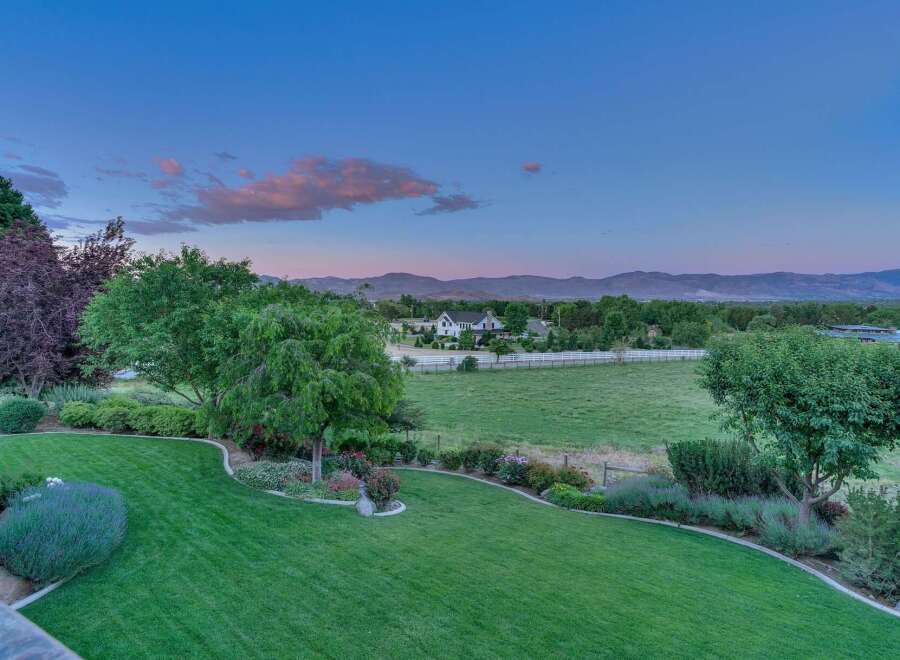 Experience serene country living with this stunning property featuring a meticulously manicured lawn and vibrant flower beds.