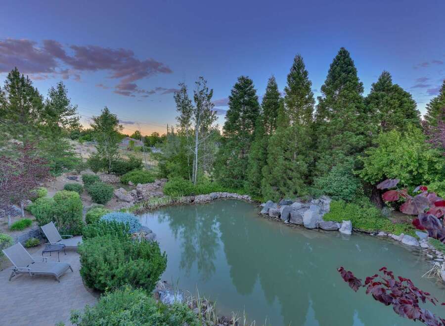 Escape to your private oasis with this stunning backyard featuring a serene pond and lush landscaping.