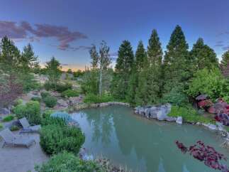 Escape to your private oasis with this stunning backyard featuring a serene pond and lush landscaping.