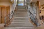 Ascend this grand staircase featuring plush carpeting and intricate wrought-iron railings with a natural, vine-like design.