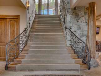 Ascend this grand staircase featuring plush carpeting and intricate wrought-iron railings with a natural, vine-like design.