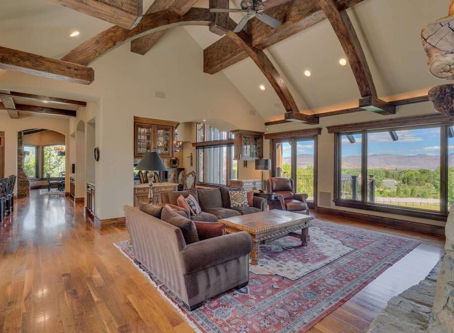 Experience luxurious living in this stunning great room, featuring soaring vaulted ceilings with exposed wooden beams and a grand stone fireplace.