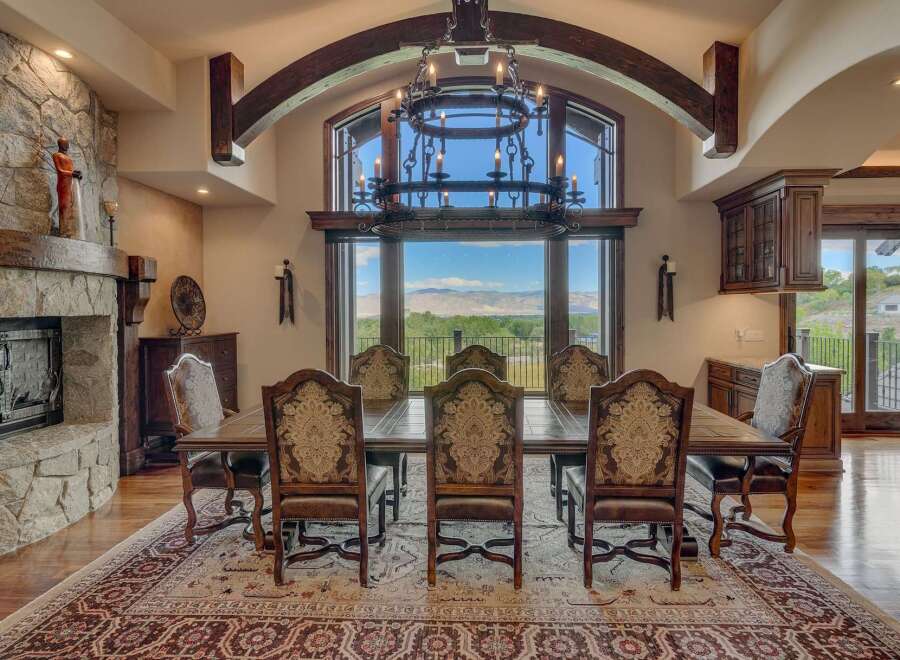 Experience elegant dining in this stunning home, featuring a grand dining room with a large stone fireplace and a magnificent chandelier.