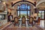 Experience elegant dining in this stunning home, featuring a grand dining room with a large stone fireplace and a magnificent chandelier.