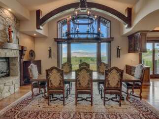 Experience elegant dining in this stunning home, featuring a grand dining room with a large stone fireplace and a magnificent chandelier.