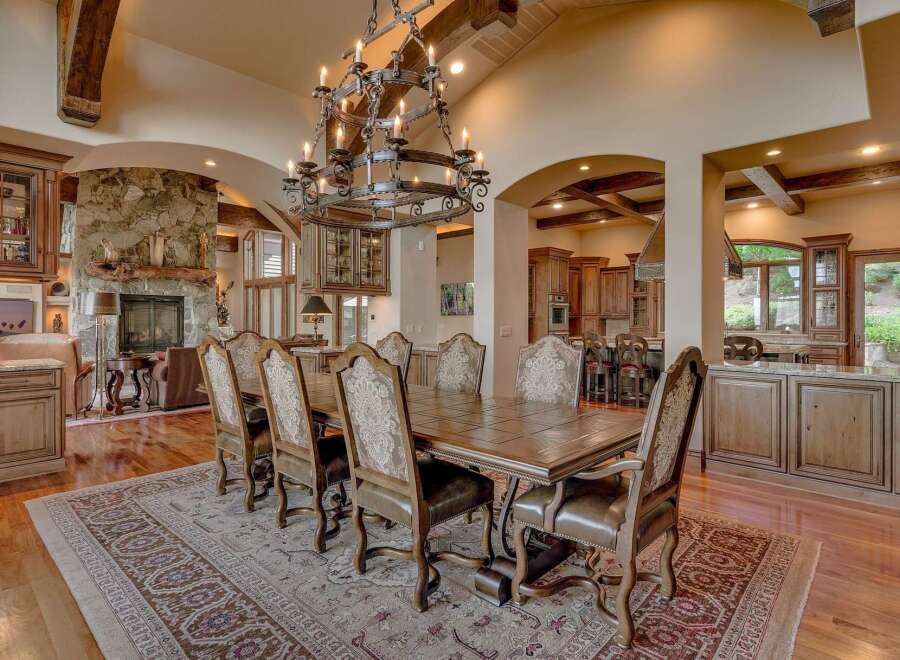 Experience luxurious dining in this grand estate, featuring a spacious dining room with a large wooden table and ornate chairs, perfect for hosting.