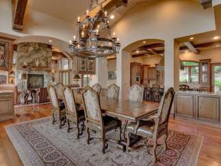 Experience luxurious dining in this grand estate, featuring a spacious dining room with a large wooden table and ornate chairs, perfect for hosting.