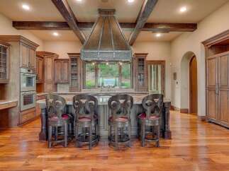 Experience luxury in this stunning kitchen featuring custom wood cabinetry and a grand copper range hood.