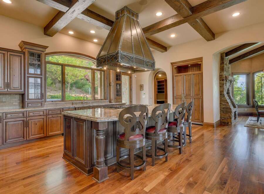 Experience luxury in this stunning gourmet kitchen, featuring custom dark wood cabinetry and a grand granite-topped island perfect for entertaining.
