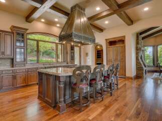 Experience luxury in this stunning gourmet kitchen, featuring custom dark wood cabinetry and a grand granite-topped island perfect for entertaining.