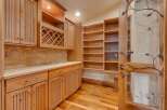 Discover this charming pantry or storage area featuring custom light wood cabinetry, including a built-in wine rack and ample shelving.