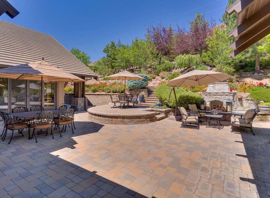 Experience luxurious outdoor living with this stunning patio featuring a stone fireplace and multiple seating areas perfect for entertaining.