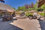 Experience luxurious outdoor living with this stunning patio featuring a stone fireplace and multiple seating areas perfect for entertaining.