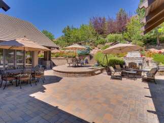 Experience luxurious outdoor living with this stunning patio featuring a stone fireplace and multiple seating areas perfect for entertaining.